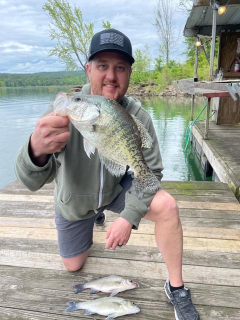 Dave kneeling on a dock holding a crappie