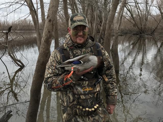 Dave in camo holding a mallard in flooded timber