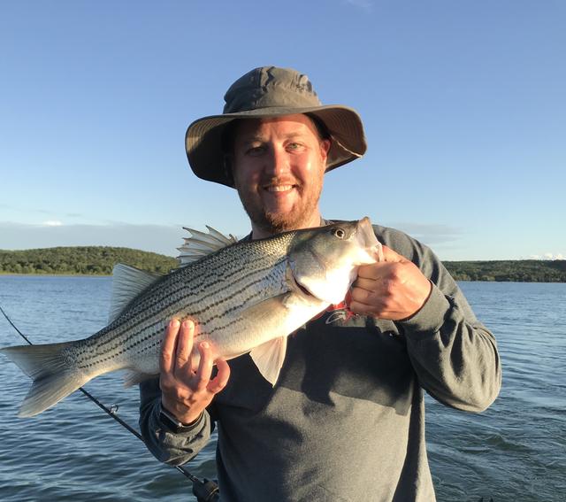 Dave in a bucket hat holding a striped bass